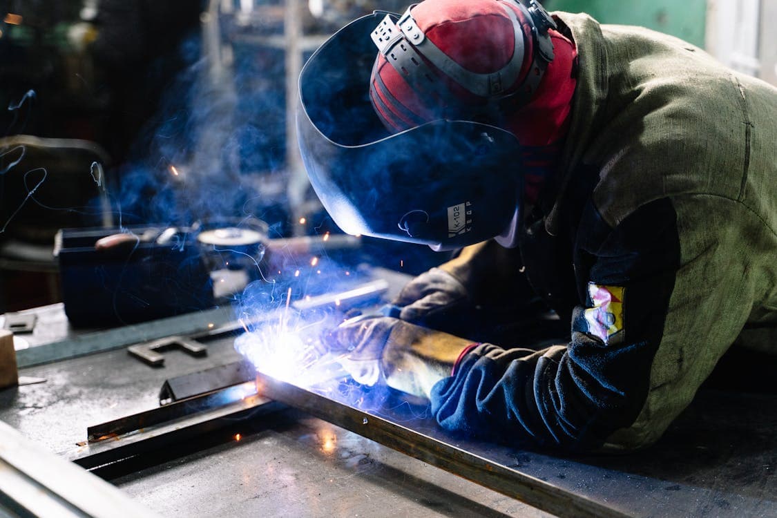 Soudeur professionnel soudant des barres métalliques avec équipement de protection